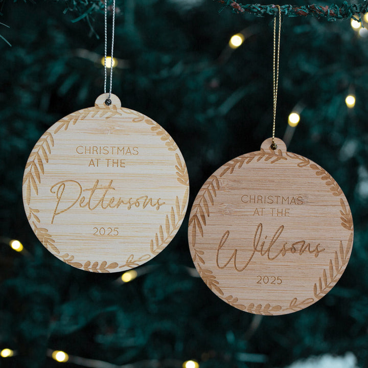 Two wooden Christmas ornaments with engraved names hanging on a tree.