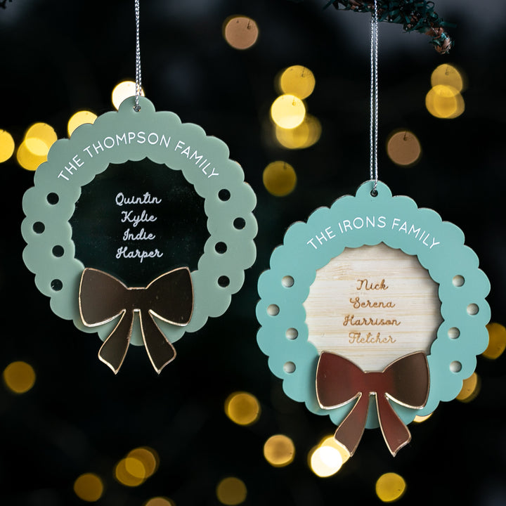 Two decorative ornaments with family names and bows against a blurred light background