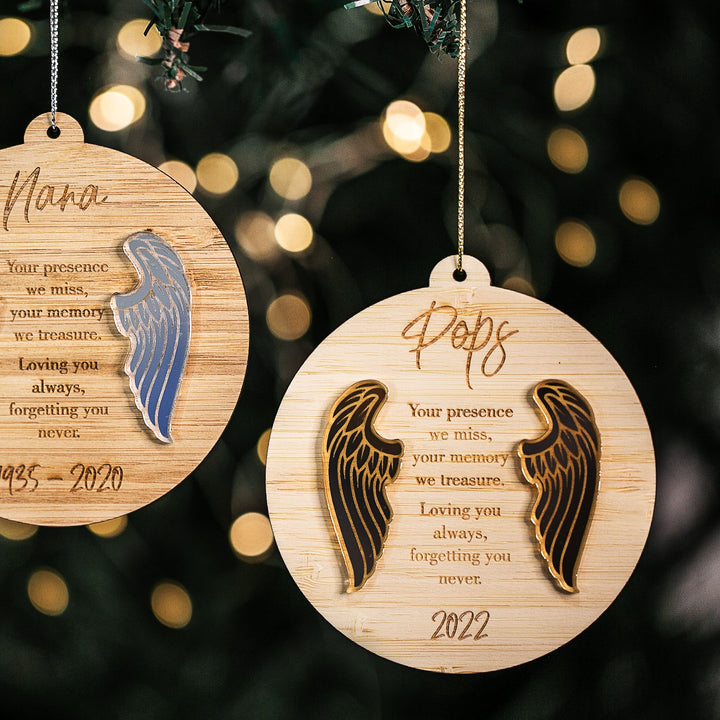 The Guardian Angel Memory Christmas Bauble, engraved with names and years like Nana and Pops, features angel wings and softly glows on the tree—an elegant ornament for cherishing loved ones during the holidays.