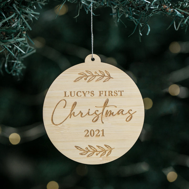 A round Christmas bauble with a bamboo-like texture, hanging from a tree. It has the text &