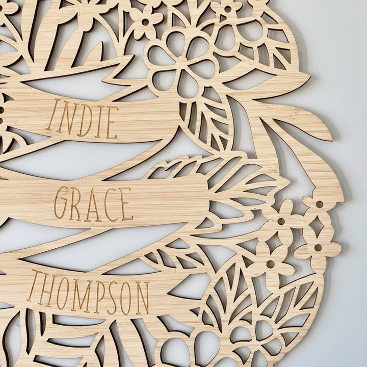 The Personalised Tropics Wall Plaque features laser-cut bamboo with floral designs and displays the name Indie Grace Thompson in script on a watercolor floral background, making it a unique addition to any space.