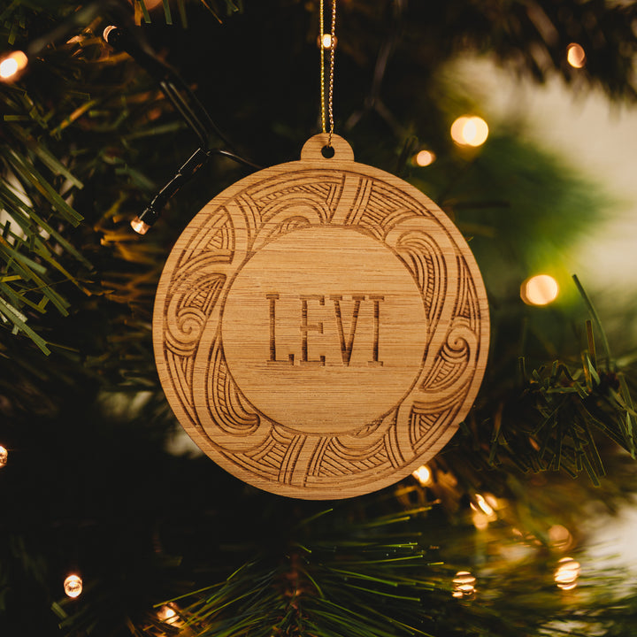 A round bamboo ornament with a Christmas tree, lights, and the name &