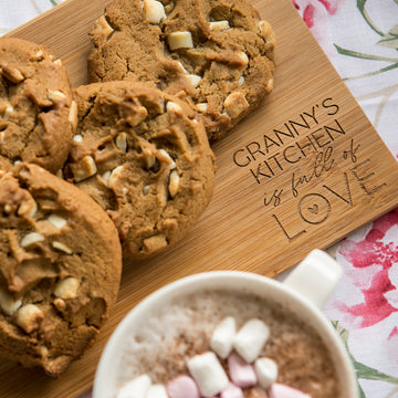 A Personalised Bamboo Platter/Serve Board (two sizes available), engraved with GRANNYS KITCHEN is full of LOVE, displays cookies by a mug of hot chocolate—an ideal gift New Zealand families will treasure.