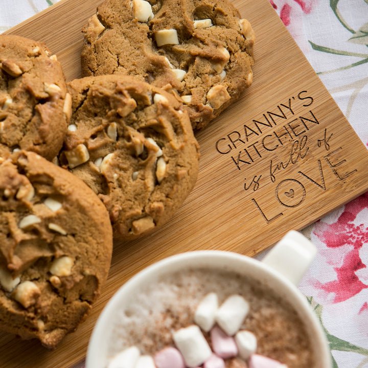 A Personalised Bamboo Platter/Serve Board (two sizes available), engraved with GRANNYS KITCHEN is full of LOVE, displays cookies by a mug of hot chocolate—an ideal gift New Zealand families will treasure.