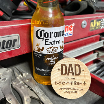 A bottle of Corona Extra sits on a red toolbox next to pliers and a Personalised Magnetic Bottle Opener (3 designs available). A wooden coaster reads: DAD YOU ARE beer-illiant. HAPPY FATHERS DAY LOVE OLLIE—a perfect personalised gift for men.
