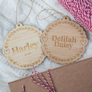 Two wooden ornaments with engraved names on a textured surface.