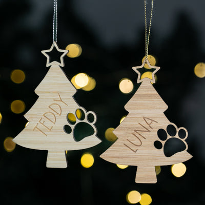 Two wooden Christmas tree ornaments with names 'Teddy' and 'Luna' on a dark background with lights.