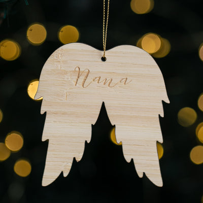 Wooden angel wing ornament with 'Nana' engraving on a blurred light background