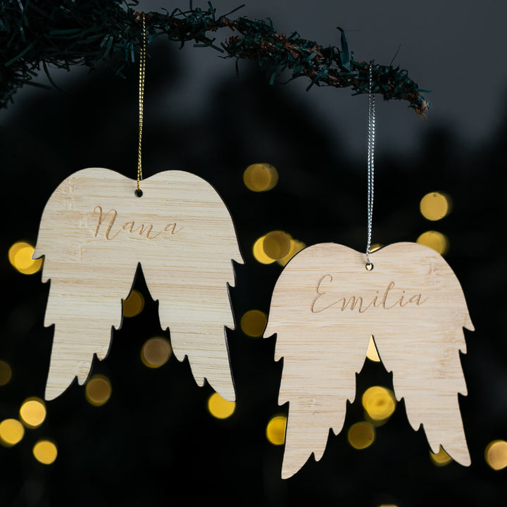 Wooden angel wing ornaments with engraved names against a festive background