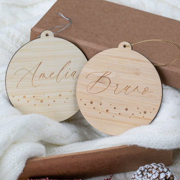 Two wooden ornaments with engraved names on a soft white surface.