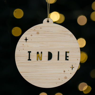 Wooden ornament with 'INDIE' text on a blurred lights background