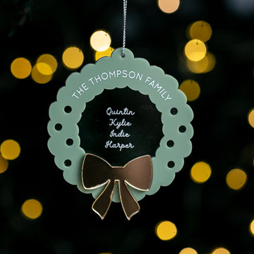 Decorative wreath ornament with a bow on a dark background with blurred lights