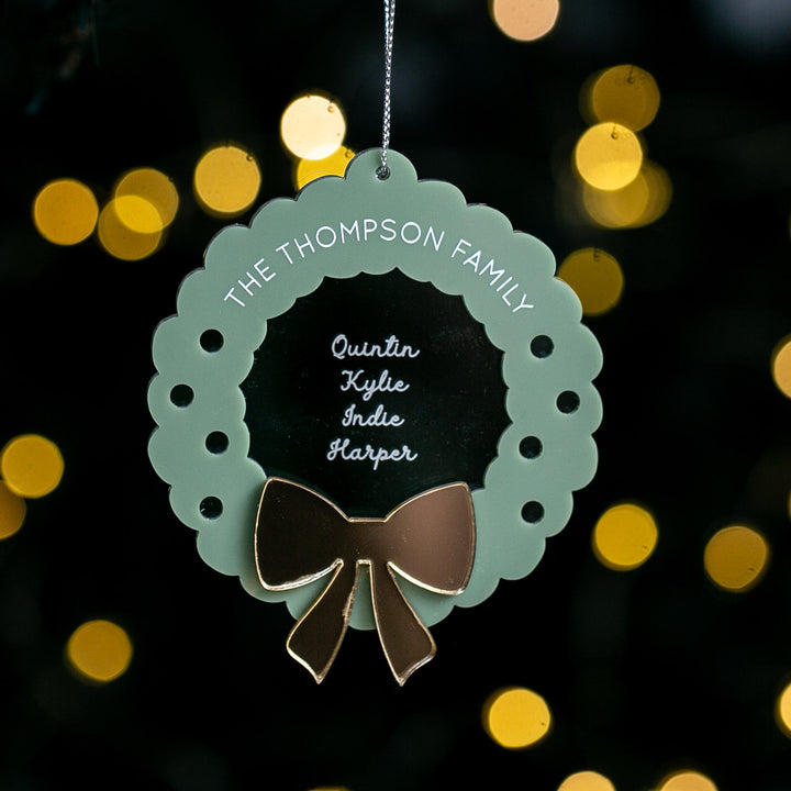 Decorative wreath ornament with a bow on a dark background with blurred lights