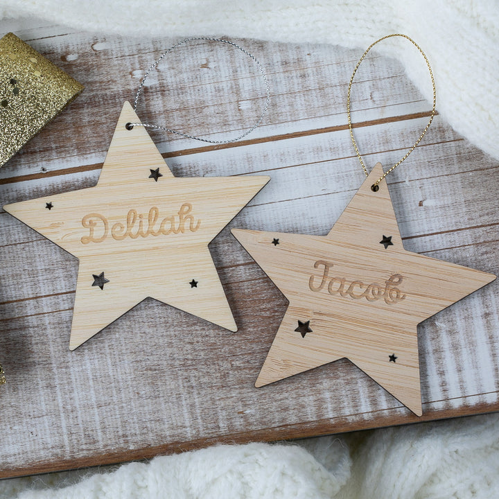 Two wooden star ornaments with engraved names on a rustic wooden surface.