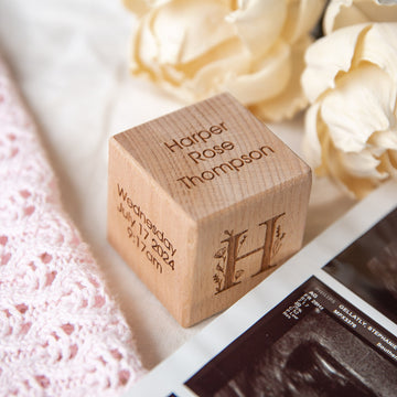 Personalised Wooden Blocks engraved with Harper Rose Thompson, Wednesday July 17, 2024, 9:17am, and a decorative H. Shown with white flowers, pink knitted fabric, and ultrasound photos—a perfect baby keepsake.