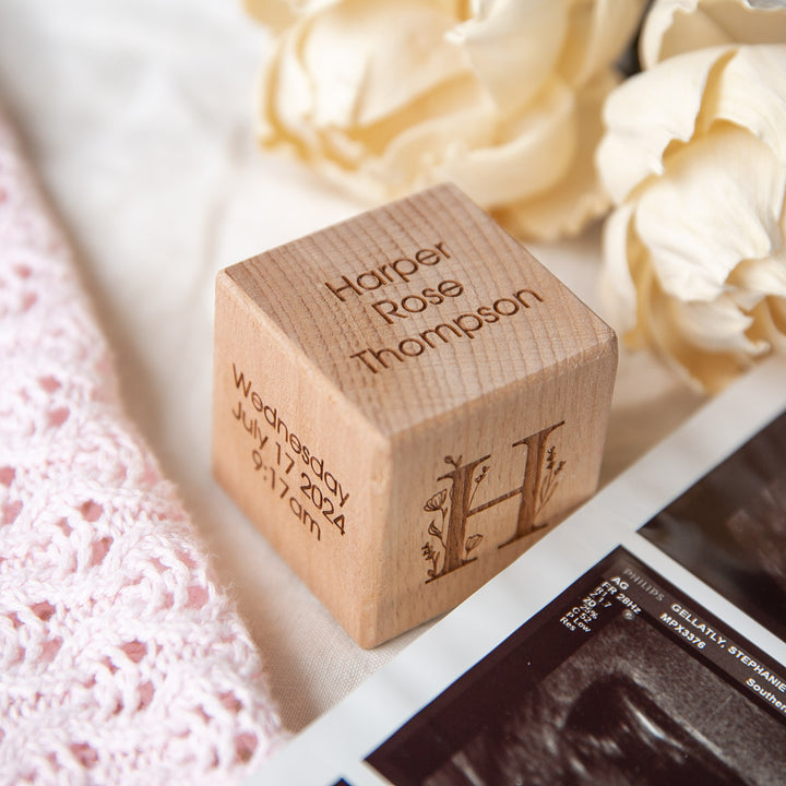 Personalised Wooden Blocks engraved with Harper Rose Thompson, Wednesday July 17, 2024, 9:17am, and a decorative H. Shown with white flowers, pink knitted fabric, and ultrasound photos—a perfect baby keepsake.