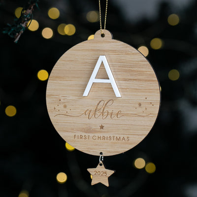 Wooden Christmas ornament with letter 'A' and 'albie' engraved, against a blurred festive background.
