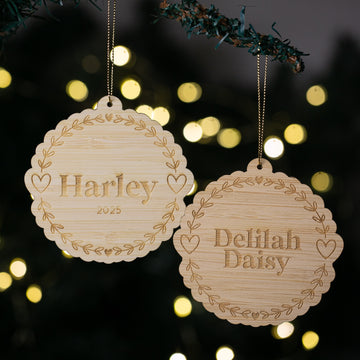 Two wooden Christmas ornaments with engraved names against a festive background