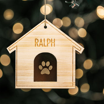 A personalized Christmas ornament with a bamboo engraved top layer and a mirrored acrylic base, featuring a paw print and the name &