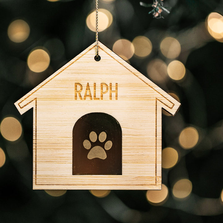 A personalized Christmas ornament with a bamboo engraved top layer and a mirrored acrylic base, featuring a paw print and the name &