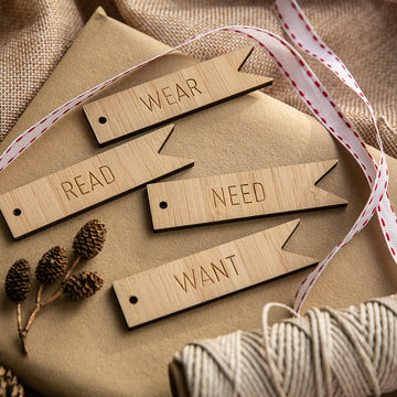 The Flag - Want, Need, Wear, Read Tags (Unpersonalised) set includes four wooden Christmas gift tags engraved with WANT, NEED, WEAR, and READ.