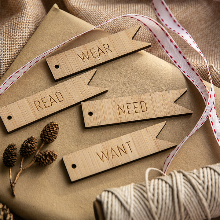 The Flag - Want, Need, Wear, Read Tags (Unpersonalised) set includes four wooden Christmas gift tags engraved with WANT, NEED, WEAR, and READ.