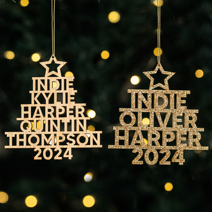 Two Whānau Christmas Tree Baubles (one wood, one gold glitter) personalised with names like Indie, Harper, and Thompson and “2024” cut out. Family ornaments shown with festive lights in the background.