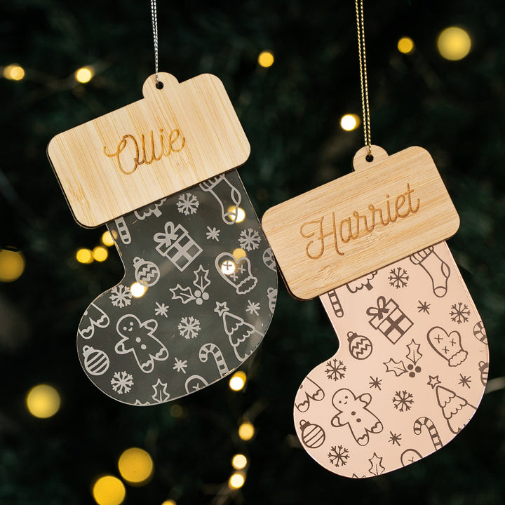 Personalised Christmas Stocking Baubles with wooden name tags—Ollie and Harriet—feature festive designs and hang before twinkling Christmas lights, making them perfect ornaments for your holiday décor.