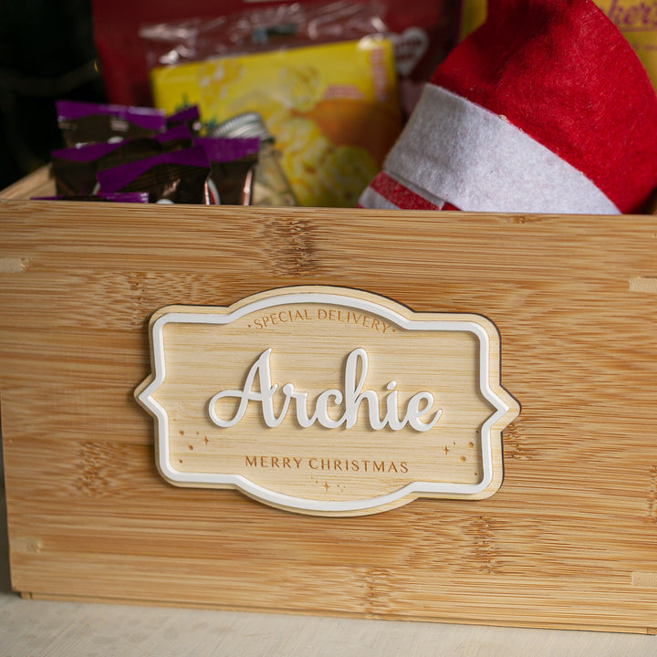 The Personalised Christmas Eve Box features a "Special Delivery Archie Merry Christmas" label and holds festive items like a Santa hat and treats—making it a perfect keepsake for family Christmas traditions.