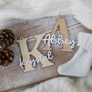 Wooden name decorations on a wooden board with pine cones and a white sock.