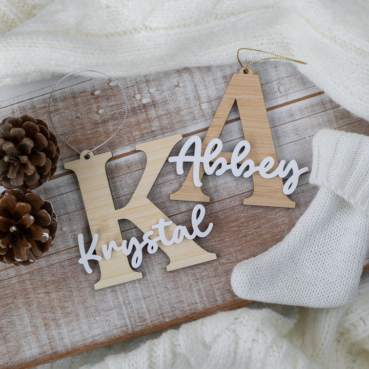Wooden name decorations on a wooden board with pine cones and a white sock.