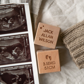 Personalised Wooden Blocks engraved with JACK ALLAN WILSON and 3.55KG 51CM are displayed next to baby ultrasound images and a knitted fabric on a soft surface—a perfect newborn gift.