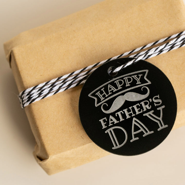 A small gift wrapped in brown paper, tied with black-and-white twine, features the Father&