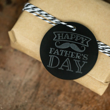 A brown gift wrapped with black and white twine is topped with a Father&