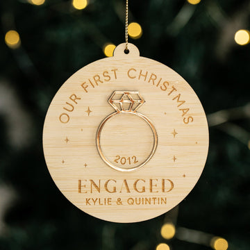 The Diamond Ring Christmas Bauble is a round eco-friendly bamboo ornament, engraved with OUR FIRST CHRISTMAS, 2012, ENGAGED, and KYLIE & QUINTIN. Perfect as a personalised engagement keepsake for your Christmas tree.