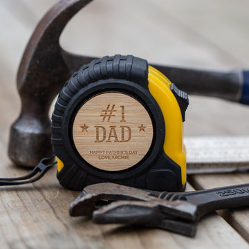 A yellow and black Personalised Tape Measure featuring a wooden badge with 
