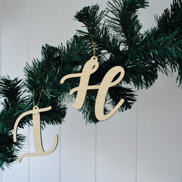 Letter Christmas Ornaments "I" and "H" hang from a green artificial pine garland against a white paneled wall.