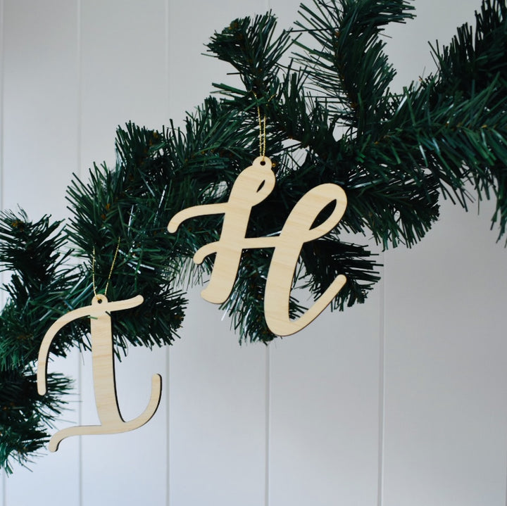 Letter Christmas Ornaments "I" and "H" hang from a green artificial pine garland against a white paneled wall.