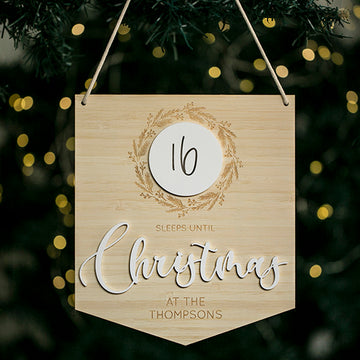 The Christmas Countdown Banner hangs on a tree with fairy lights, displaying "16 sleeps until Christmas at the Thompsons"—16 in a white circle and Christmas in large cursive—a unique personalised festive decoration.