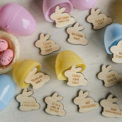Little bamboo laser cut bunnies with activities engraved into them, surrounded by plastic easter hunt eggs