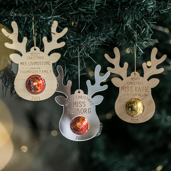 Personalised Teachers Reindeer Treat Christmas Ornaments hang on the tree, each with a name and space for a Lindt ball. Engraved with "Merry Christmas 2021," they make ideal teacher gifts or unique holiday decorations.