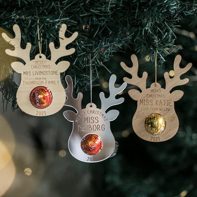 Personalised Teachers Reindeer Treat Christmas Ornaments hang on the tree, each with a name and space for a Lindt ball. Engraved with "Merry Christmas 2021," they make ideal teacher gifts or unique holiday decorations.