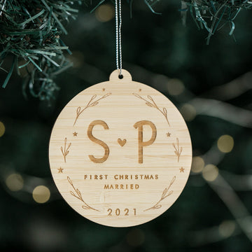 The Lovers Christmas Bauble is a wooden ornament engraved with S ♥ P, First Christmas Married, and 2021, surrounded by a wreath design—an ideal wedding gift or personalised bauble for your tree.