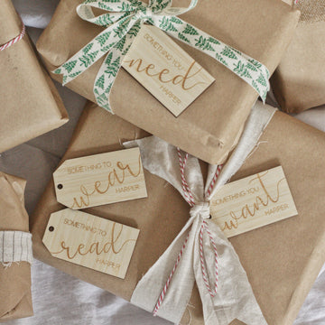 A group of presents wrapped in brown paper and string, each with a "Personalised - Want, Need, Wear, Read Tag" featuring Harper’s name: “Something you need,” “Something to wear,” “Something to read,” and “Something you want.”.