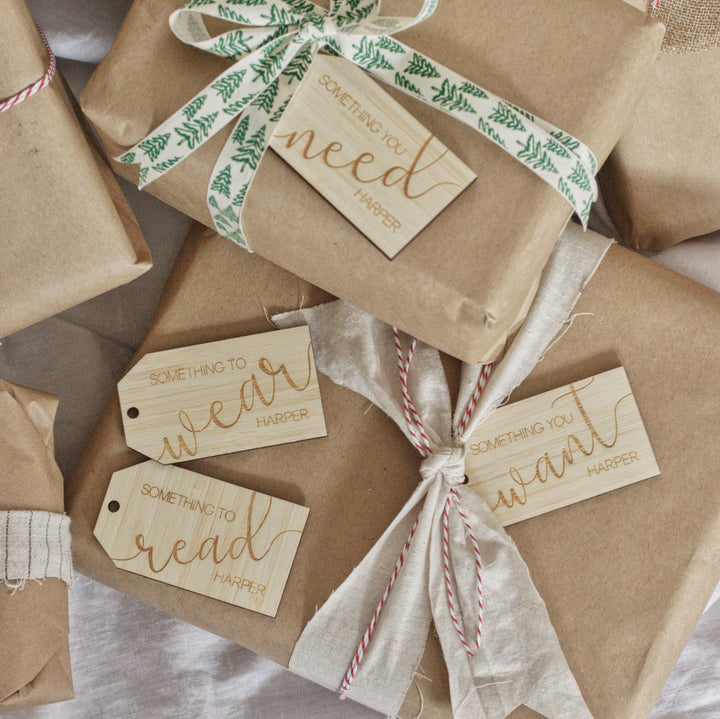 A group of presents wrapped in brown paper and string, each with a "Personalised - Want, Need, Wear, Read Tag" featuring Harper’s name: “Something you need,” “Something to wear,” “Something to read,” and “Something you want.”.