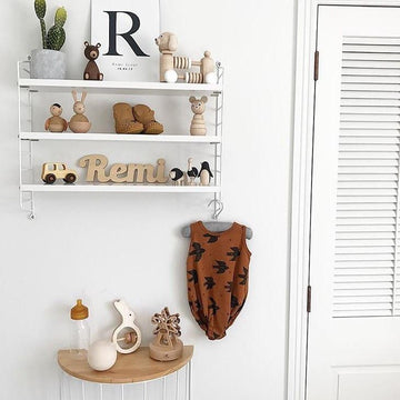 A bamboo wall name saying Remi, sitting on a shelf in a children&