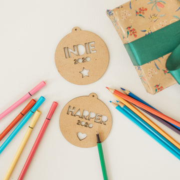Two wooden Christmas baubles with personalized engravings, one labeled &