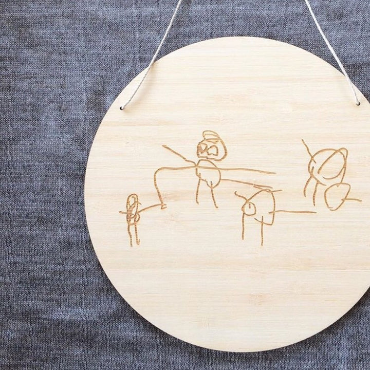 A round light bamboo plaque with a childs drawing engraved on it. 