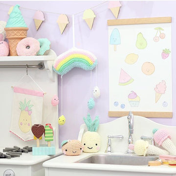 A light bamboo garland with 7 icecreams, each painted yellow, pink and orange. Hanging in a child&