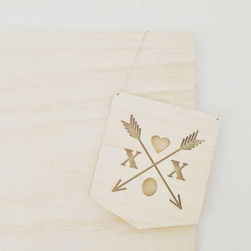 The XOX Crest Banner is a light bamboo wall banner featuring two crossed arrows, a heart, two Xs, and an oval cutout. Hangs by string against any background.